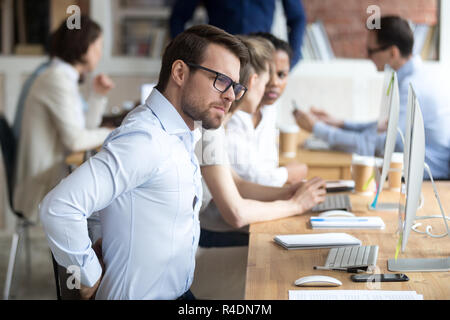 Stressed exhausted businessman massaging back after long work  Stock Photo