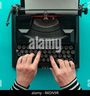 Woman typing vintage typewriter, top view of hands on blue background Stock Photo