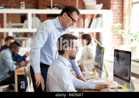 Middle aged mentor helping employee with computer work  Stock Photo