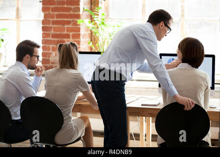 Middle aged mentor helping female employee with computer work Stock Photo