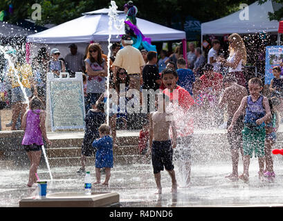 A little boy gasps in shock at the cold water, as another laughs at his discomfort, in the water feature 'Splashville' in Asheville, NC, USA Stock Photo