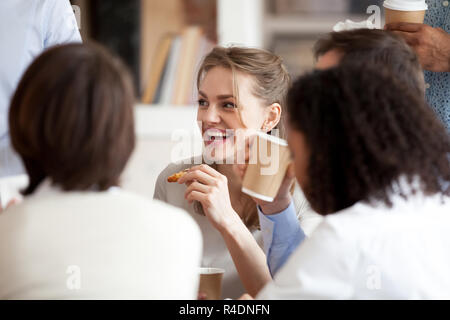 Smiling businesswoman eating pizza with colleagues on break Stock Photo