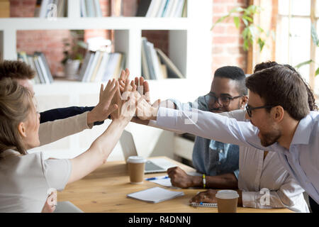 Excited multiracial team giving high five at company meeting Stock Photo