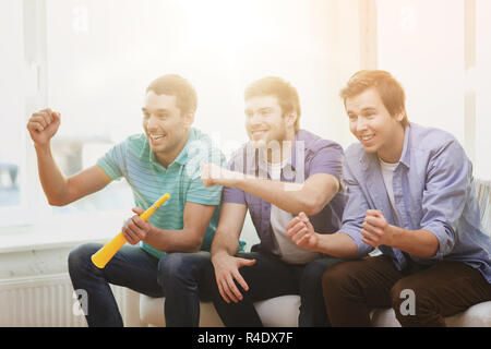 happy male friends with vuvuzela watching sports Stock Photo