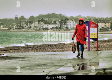 Weymouth, Dorset. 27th November 2018. A woman struggles along the seafront in the rain Credit: stuart fretwell/Alamy Live News
