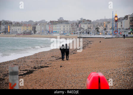 Weymouth, Dorset. 27th November 2018. A couple walk along the beach in the rain Credit: stuart fretwell/Alamy Live News