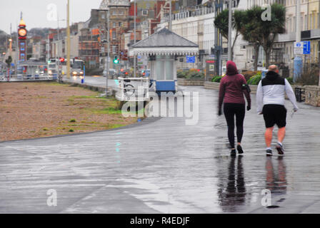Weymouth, Dorset. 27th November 2018. A couple walk along the seafront in the rain Credit: stuart fretwell/Alamy Live News
