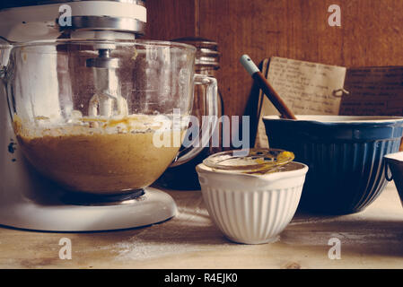 Ingrediens are mixed  to prepare some pumpkin muffin for halloween are displayed, frontal view, with stand mixer on a rustic environment Stock Photo