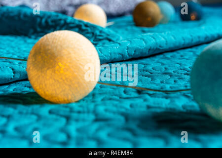 Christmas Decoration Light Balls Laying on Mattress with Turquoise Background Stock Photo