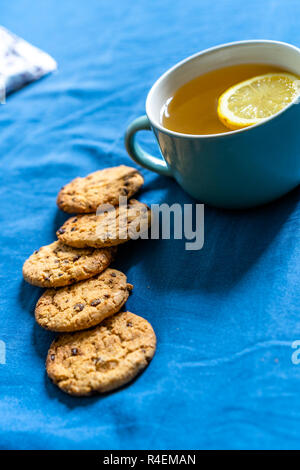 Tea with Lemon and Cookies with Chocolate Laying on Mattress - Blurred Turquoise Cover in Background with Pillow Stock Photo