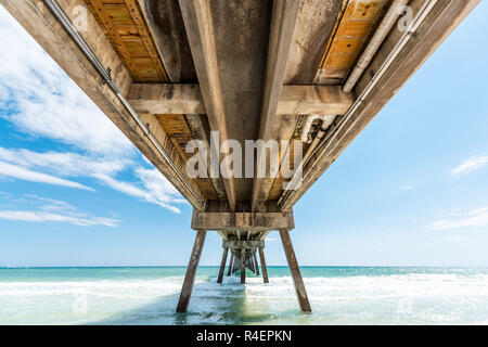 Under, underneath Okaloosa island fishing pier in Fort Walton Beach, Florida with pillars, green shallow waves in Panhandle, Gulf of Mexico during sun Stock Photo