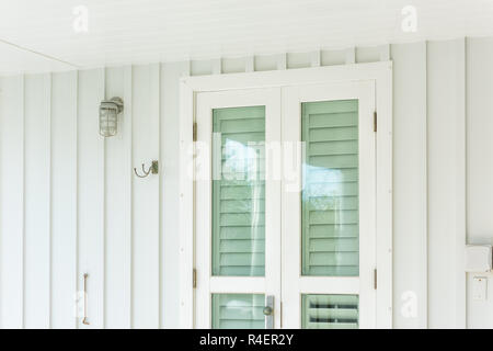 Pastel green colorful hurricane window shutters architecture open exterior of house in Florida beach home apartment building during day entrance, glas Stock Photo