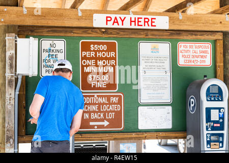 Sanibel Island, USA - April 29, 2018: Bowman's beach near Captiva Island with man paying parking fee at pay machine, signs Stock Photo