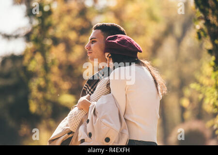 Beautiful, young couple is spending nice day in the autumn park, looking peacfully while hugging Stock Photo