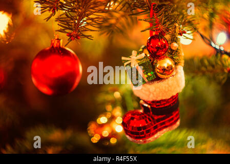 Miniature Boot filled with Presents hanging in Christmas Tree Stock Photo
