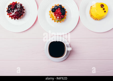 Flat lay composition of delicious small cakes with espresso on pink wooden table, top view. Stock Photo