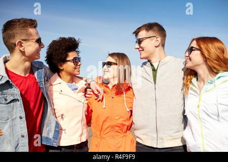 happy teenage friends in shades talking on street Stock Photo