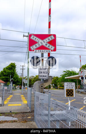 Australian railway crossing red with white cross waning sign on road, with keep tracks clear, stop at red on signal signs, NSW, Australia Stock Photo