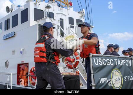 Crew members from Coast Guard Cutter Tarpon, an 87-foot Coast Patrol Boat homeported in St. Petersburg, Florida, offload 1,735 kilograms of cocaine, an estimated wholesale value of $56 million and transfer custody of eight suspected drug smugglers Wednesday, May 3, 2017 at Coast Guard Sector St. Petersburg, Florida. The contraband and suspected smugglers were interdicted during four separate cases supporting Operation Martillo, a joint interagency and multi-national collaborative effort among 14 Western Hemisphere and European nations to stop the flow of illicit cargo by Transnational Criminal Stock Photo