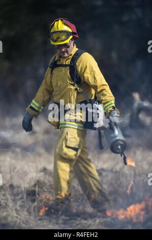 U.S. Air Force Senior Airman Grant Kopplin, a fire protection specialist assigned to the 673d Civil Engineer Squadron, uses a drip torch to light a back fire during a controlled burn at the Infantry Platoon Battle Course on Joint Base Elmendorf-Richardson, Alaska, May 5, 2017. Controlled burns consume accumulated dry brush and grass thereby reducing the risk of wildfires. Kopplin is a native of Willard, Mo. Stock Photo