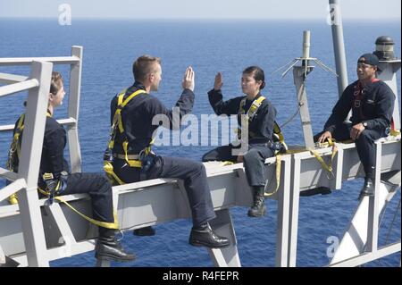 MEDITERRANEAN SEA (May 3, 2017) Lt. Cmdr. Ben McCarty, second from left, reenlists Information Systems Technician 2nd Class Nikki Duffy on the yardarm of the Arleigh Burke-class guided-missile destroyer USS Ross (DDG 71). Ross, forward-deployed to Rota, Spain, is conducting naval operations in the U.S. 6th Fleet area of operations in support of U.S. national security interests in Europe and Africa. Stock Photo