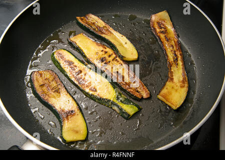 fried zucchini slices in a black pan, delicious vegetables, Mediterranean style cooking, view from above Stock Photo