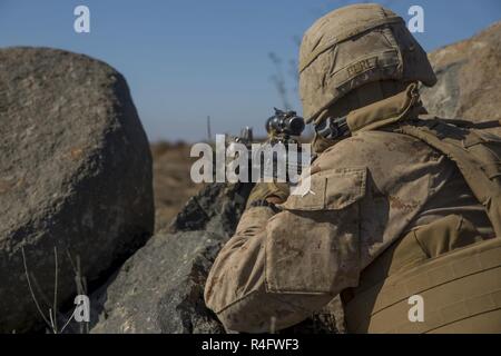 Pfc. Elmer Perez, a scout rifleman with 1st Light Armored Reconnaissance Battalion, 1st Marine Division, takes up a defensive position during a field exercise aboard Marine Corps Base Camp Pendleton, Calif., Oct. 25, 2016. The exercise was held as part of a week-long Marine Corps Combat Readiness Evaluation to ensure combat readiness before deployments. Marines maintain coverage over an area and stay alert of any enemy activity while in their defensive positions. Stock Photo