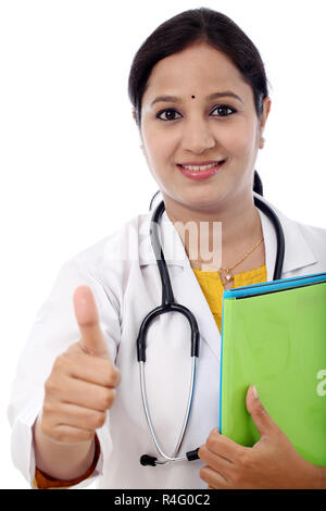 Young Indian Female Doctor showing thumbs up against white background Stock Photo