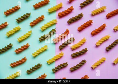 Italian pasta pattern on pink green background. Various colors of pasta viewed from above. Top view. Repetition. Full frame.Raw Italian pasta.Flat lay of uncooked pasta on double colorful background. Stock Photo