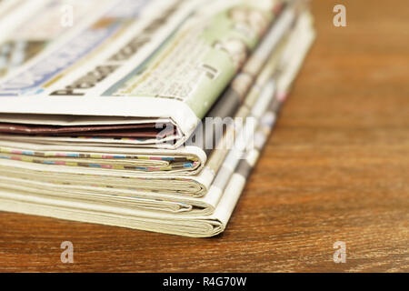 Pile of fresh morning newspapers on table at office. Latest financial and business news in daily paper. Pages with data. Folded and stacked journals Stock Photo