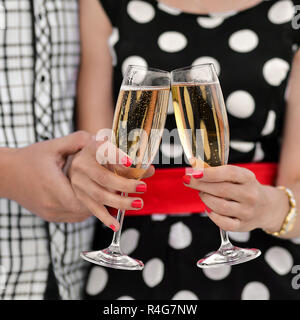 Two glasses with champagne and hands. Young happy family celebrate new date,happy birthday,anniversary.Young happy family celebrate new date,happy birthday,anniversary. Couple celebrates the anniversary, drinks champagne, has fun and enjoys life. Couple a Stock Photo