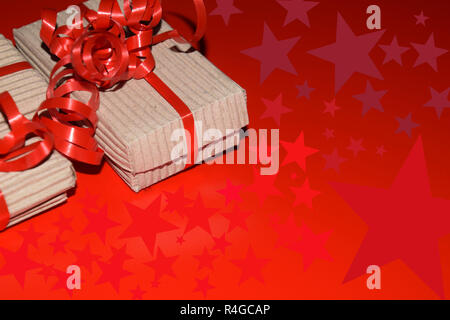 star symbols and gifts for christmas with copy space, top view of gift box wrapped in cardboard packaging with red ribbon on red surface Stock Photo