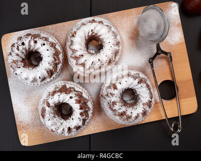 Miniature Chestnut Bundt Cakes with Chocolate Chips on a bamboo cutting board, on a dark brown background Stock Photo
