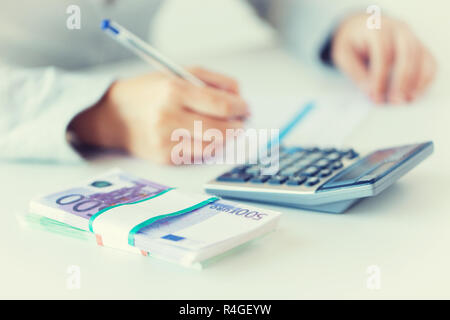 close up of hands counting money with calculator Stock Photo