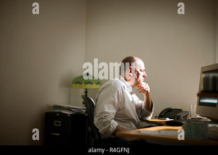 Businessman sitting at a computer inside an office. Stock Photo