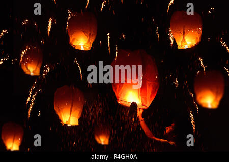 Man holding flying fire lantern to celebrate festival in a night against dark sky. Stock Photo