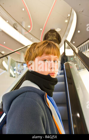 child on moving staircase looks self confident and smiles Stock Photo