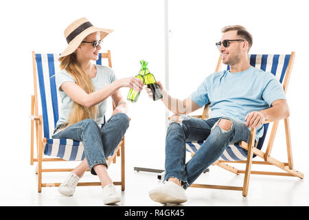 Couple sitting on deck chairs, relaxing and drinking beer isolated on white Stock Photo