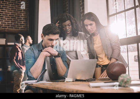 concentrated casual businesspeople working together using computer in loft office with backlit Stock Photo