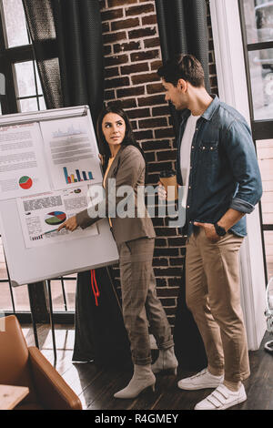 concentrated couple of colleagues discussing project using marketing graph in loft office Stock Photo