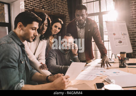 serious multiethnic group of colleagues working together on new project in modern loft office with backlit Stock Photo