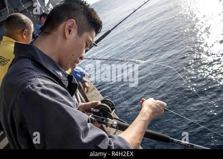EASTERN PACIFIC OCEAN (Sept. 30, 2018) Command Master Chief Francisco  Valdovinos reels in line during a fishing call aboard amphibious assault  ship USS Boxer (LHD 4). Boxer is underway conducting routine operations