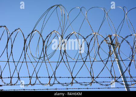 Barbed wire and Concertina wire atop the border wall separating the United States and Mexico. Stock Photo