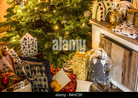 Small handmade gift boxes in shiny colorful night christmas tree setup background celebration. Stock Photo