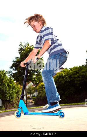 boy enjoys riding his scooter at the skate park Stock Photo