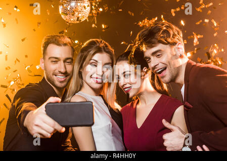 group of happy friends taking selfie with smartphone during party Stock Photo