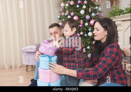 happy caucasian family boy man and woman with gift boxes and christmas tree with toys Stock Photo