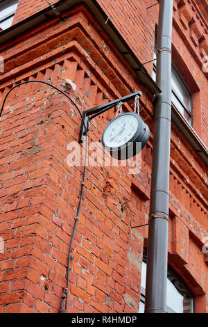 clock on a brick building on the street hanging on the corner Stock Photo
