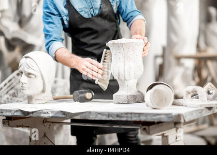 Man working with stone vase at the working place in the old studio. Close-up view with no face Stock Photo