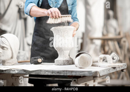 Man working with stone vase at the working place in the old studio. Close-up view with no face Stock Photo